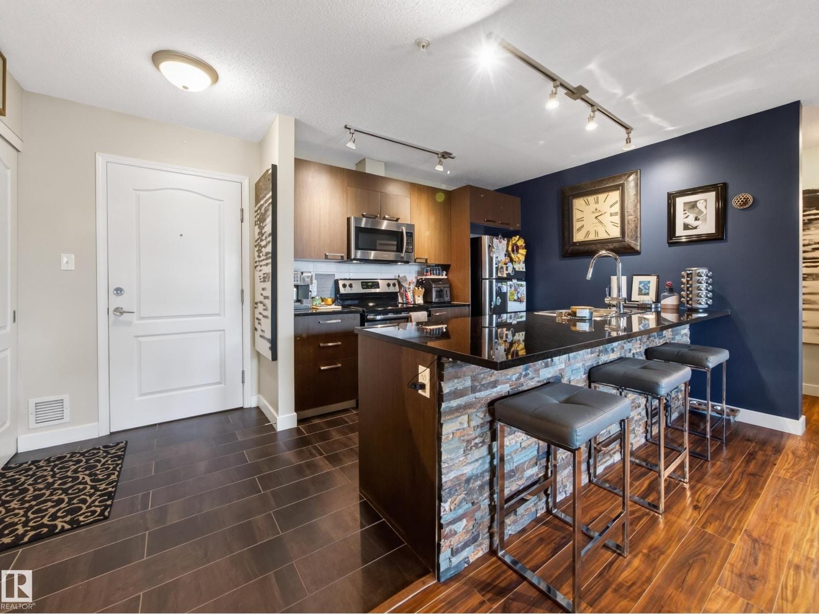Open kitchen and living space with navy accent wall and stone-clad island