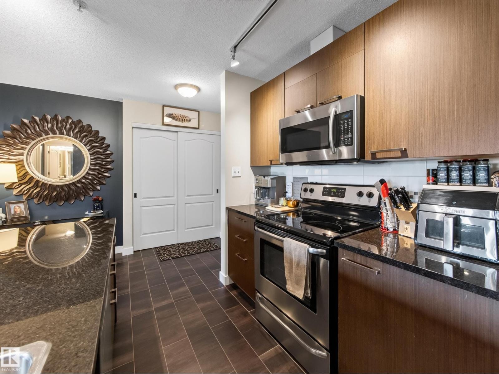 Kitchen with granite counters, stainless range and dark cabinetry