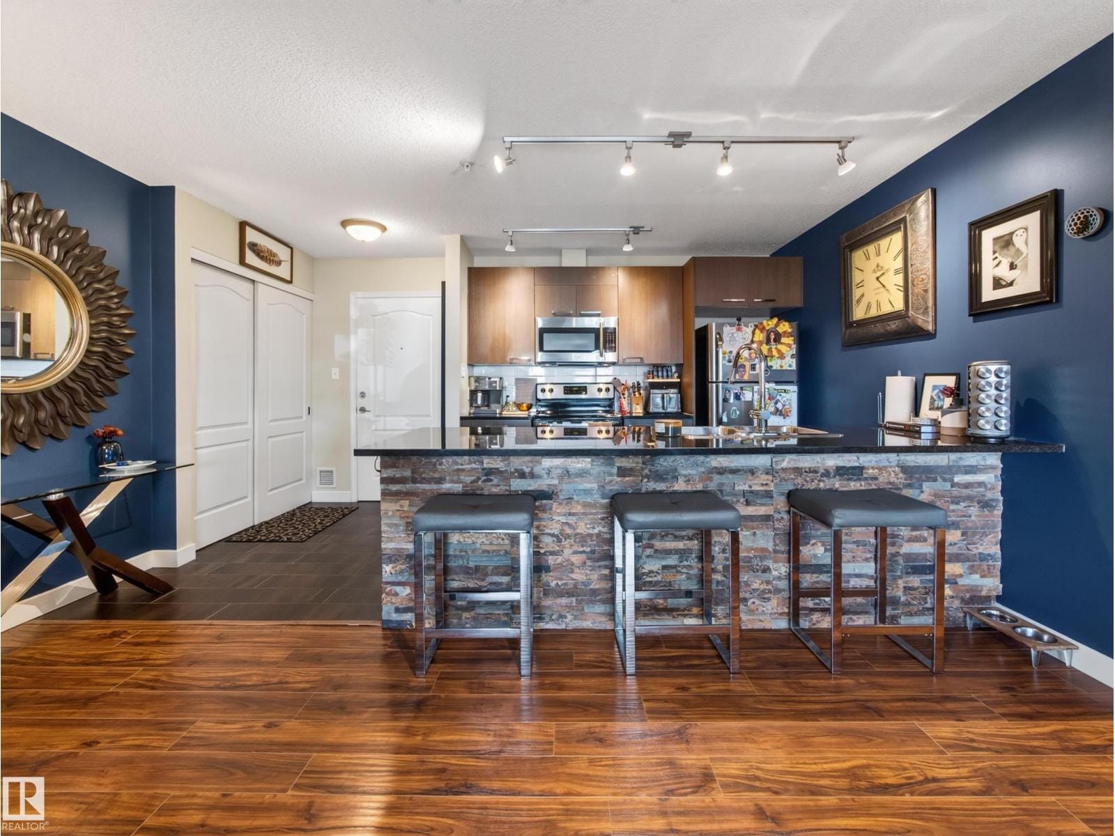 Kitchen island with breakfast bar seating under track lighting