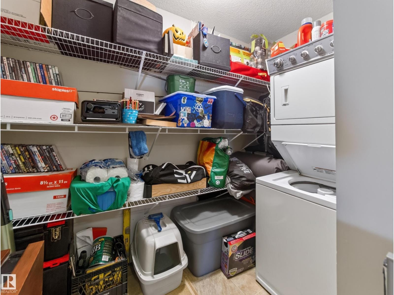 In-suite laundry with stacked washer and dryer and shelved storage room