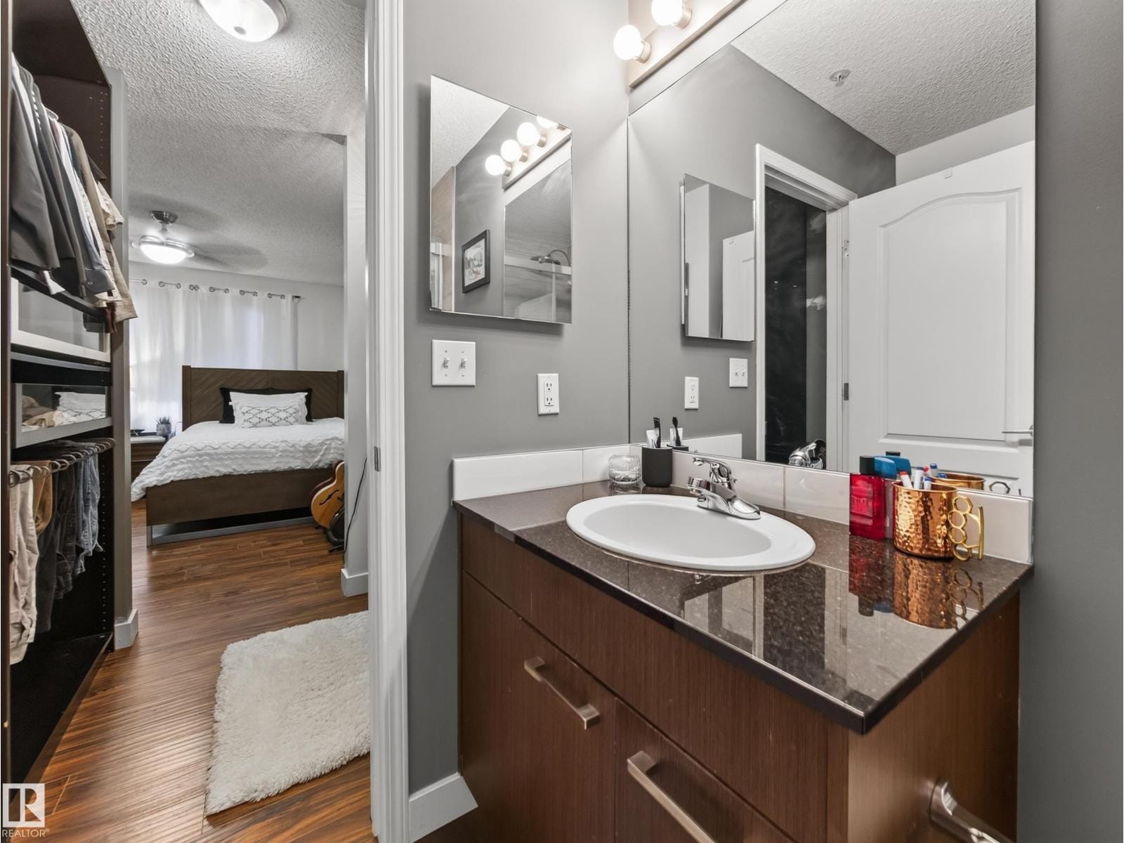 Ensuite vanity with granite counter, primary bedroom beyond