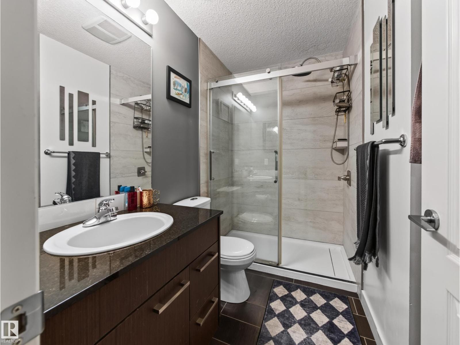 Full bathroom with glass sliding shower, dark vanity and tile floor