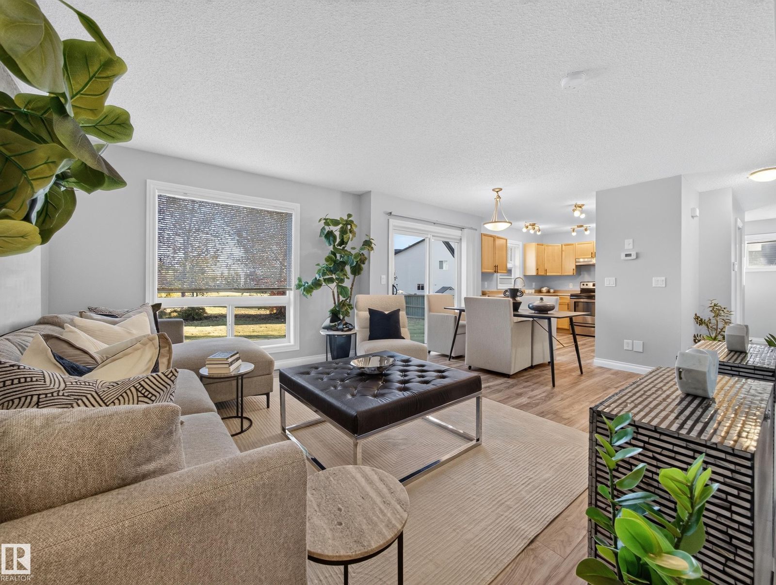 Staged living room with sectional, window and the kitchen beyond