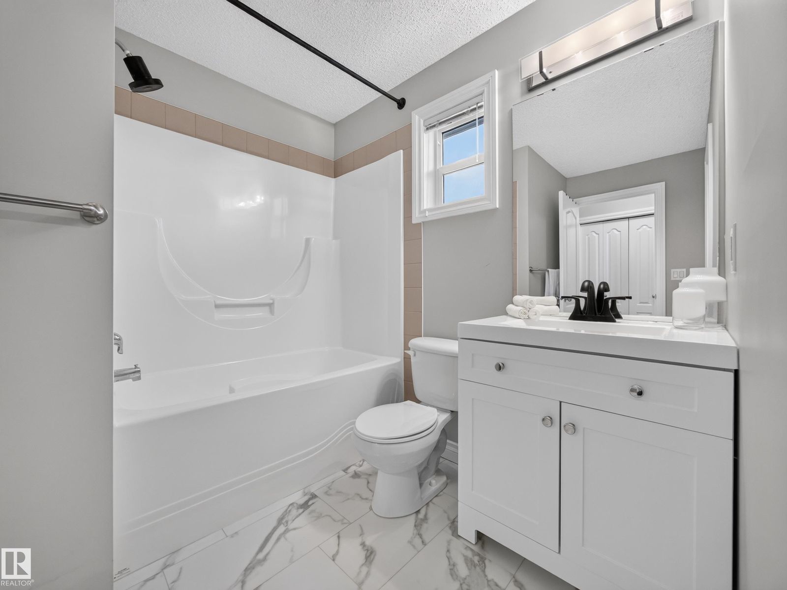 Four-piece bathroom with tub and marble-look floor