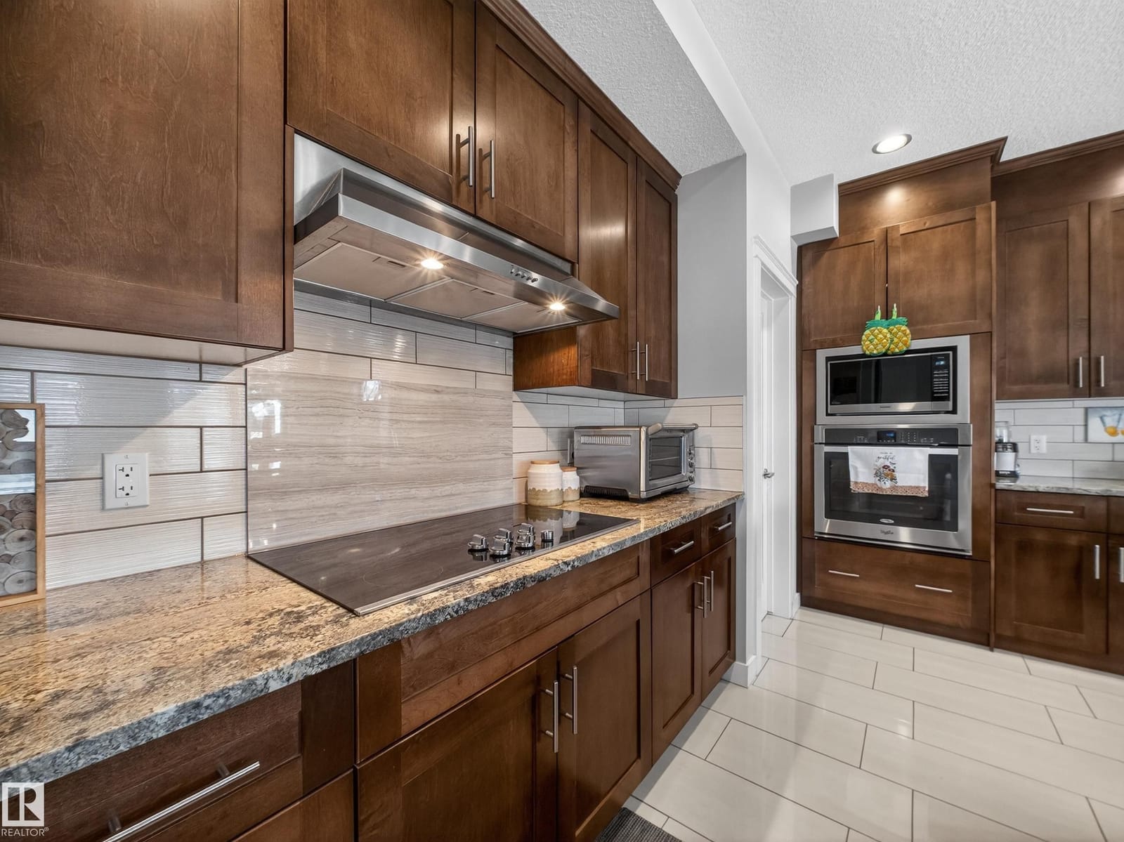 Cooktop, tile backsplash and granite counters