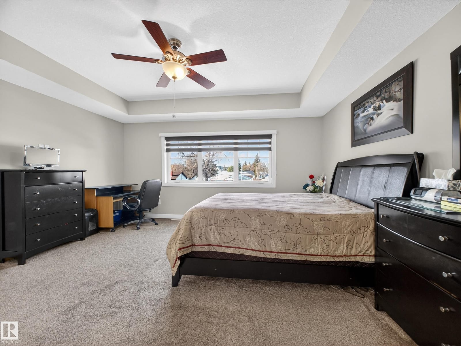 Primary bedroom with tray ceiling and ceiling fan