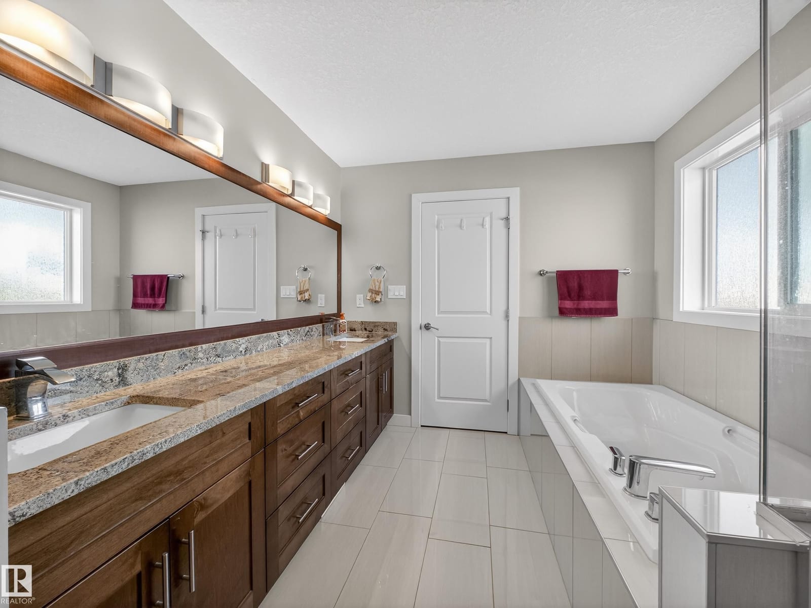 Ensuite vanity and soaker tub with tile flooring